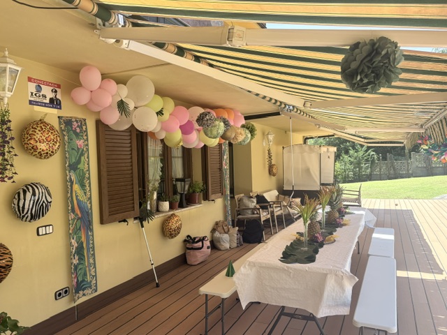 Escenografía temática de selva con guirnalda de globos, estampados de leopardo y mesa con hojas tropicales